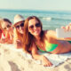 Ragazze sorridenti con smartphone sulla spiaggia