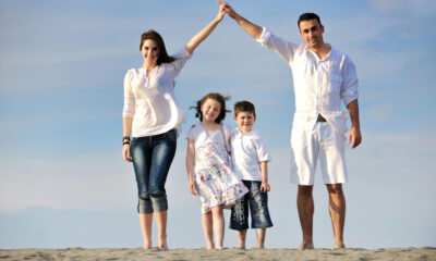 Famiglia sulla spiaggia mostra il segno della casa