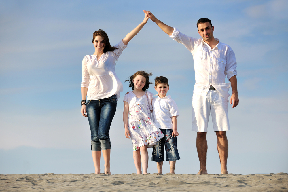 Famiglia sulla spiaggia mostra il segno della casa