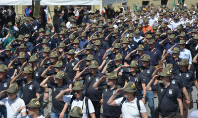 Alpini schierati in uniforme mentre eseguono il saluto militare durante l’Adunata Nazionale a Biella 2025.