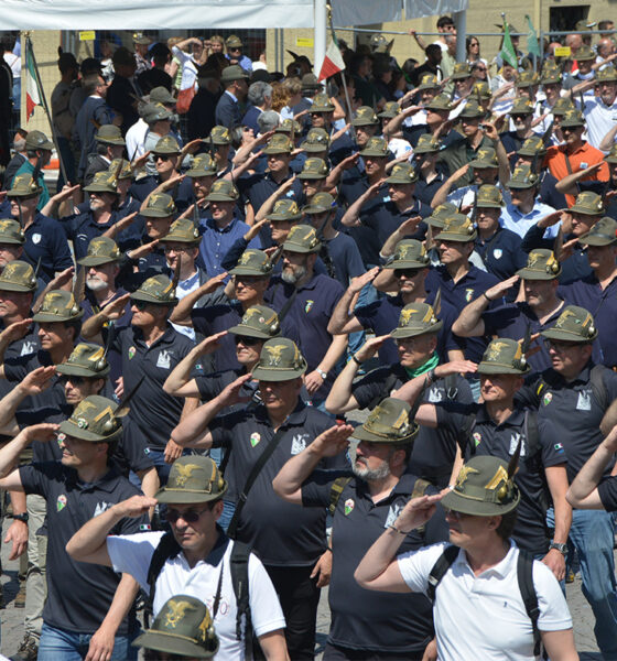 Alpini schierati in uniforme mentre eseguono il saluto militare durante l’Adunata Nazionale a Biella 2025.