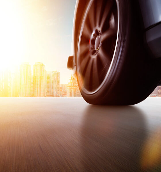 Vista laterale a basso angolo dell'auto che guida veloce al tramonto con effetto velocità di movimento