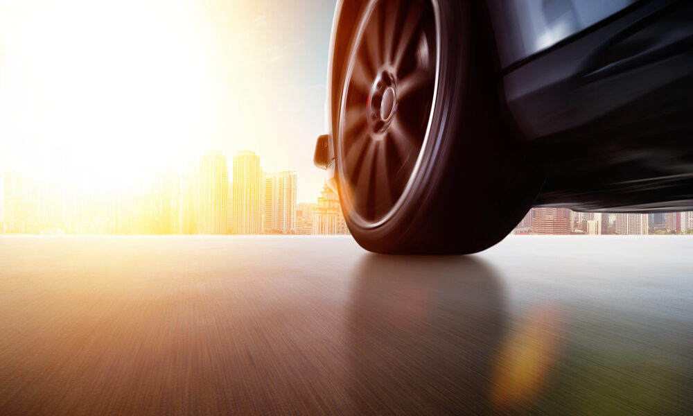 Vista laterale a basso angolo dell'auto che guida veloce al tramonto con effetto velocità di movimento