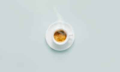 Cup of fresh made steaming coffee served in cup on blue background. Coffee background.