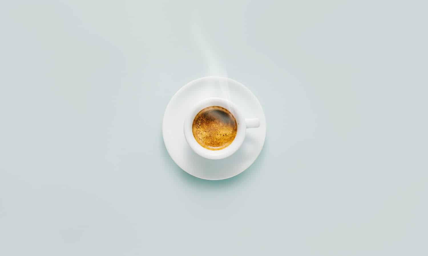 Cup of fresh made steaming coffee served in cup on blue background. Coffee background.