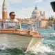 Un’imbarcazione a motore naviga nella laguna veneziana; un dispositivo di rilevamento della velocità è accennato in primo piano.