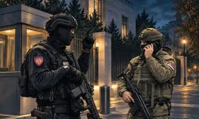 Illustrazione di due gendarmi anonimi in servizio presso l’ingresso di una sede diplomatica, in un contesto di sicurezza rafforzata.