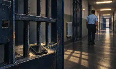Illustrazione di un telefono cellulare anonimo tra le sbarre di un corridoio penitenziario.