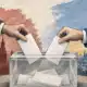Un’urna elettorale trasparente con due schede anonime, illustrazione del ballottaggio presidenziale in Bulgaria.