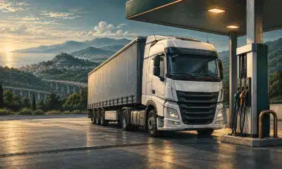 Illustrazione di un camion per il trasporto merci accanto a una pompa di carburante.