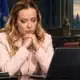 Ritratto illustrato di Giorgia Meloni accanto a un computer portatile senza testo sullo schermo.