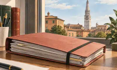 Un fascicolo chiuso in primo piano e la torre Ghirlandina sullo sfondo, in un’illustrazione editoriale sulla Procura di Modena.