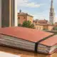 Un fascicolo chiuso in primo piano e la torre Ghirlandina sullo sfondo, in un’illustrazione editoriale sulla Procura di Modena.