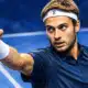Illustrazione editoriale di un tennista ispirato alla foto di riferimento, in primo piano con il pugno alzato davanti a uno sfondo blu.