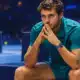 Illustrazione editoriale di un tennista seduto sulla panchina a bordo campo, ispirato al protagonista della foto di riferimento, con il campo indoor sullo sfondo.