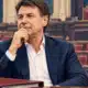 Ritratto editoriale di Giuseppe Conte davanti a un’aula parlamentare appena accennata e a un fascicolo chiuso.