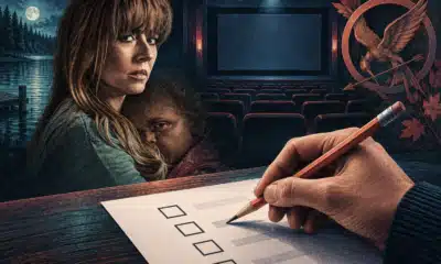 Una mano anonima tiene una matita sopra una scheda bianca, davanti a uno schermo cinematografico spento.