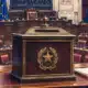 Un’urna per il voto parlamentare in primo piano, con l’aula di Montecitorio sullo sfondo.