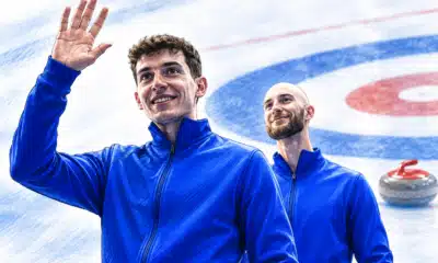 Illustrazione di due atleti della squadra italiana di curling in primo piano, con una stone e la casa sul ghiaccio sullo sfondo.