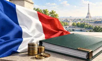 Drapeau francese accanto a un dossier di bilancio senza scritte e a poche monete.