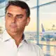 Ritratto illustrato di Flávio Bolsonaro su uno sfondo chiaro con un richiamo essenziale a un terminal aeroportuale.