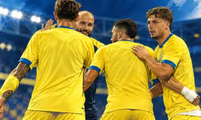 Giocatori del Frosinone in maglia gialla raccolti in una celebrazione di squadra.