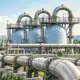 Illustrazione di serbatoi di gas e condotte interconnesse in un impianto industriale.