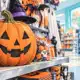 Illustrazione di una zucca decorativa in primo piano su uno scaffale con prodotti a tema Halloween.