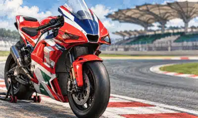 Una moto da MotoGP rossa, bianca e blu ferma accanto a una curva del circuito di Sepang.