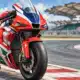 Una moto da MotoGP rossa, bianca e blu ferma accanto a una curva del circuito di Sepang.