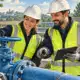 Due addetti presso una condotta idrica e una valvola, in un impianto di trattamento dell’acqua.
