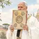Ritratto illustrato di Leone XIV, basato sulla foto di riferimento, mentre tiene un libro davanti a un fondale chiaro e neutro.
