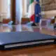 Un fascicolo di bilancio chiuso su un tavolo istituzionale, con una sala riunioni sullo sfondo