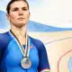 Ritratto illustrato di una ciclista in tenuta blu con una medaglia d’argento sul petto; il volto è ispirato alla foto di riferimento di Claudia Cretti.