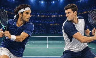 Un campo da tennis indoor vuoto con la rete al centro e due racchette ai lati opposti.