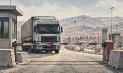 Una barriera abbassata blocca un camion davanti a un valico di frontiera vuoto.