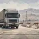 Una barriera abbassata blocca un camion davanti a un valico di frontiera vuoto.