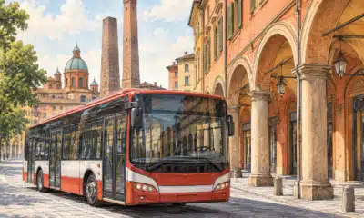 Un autobus urbano in una strada di Bologna, con i portici sullo sfondo, in un’illustrazione editoriale sullo sciopero dei trasporti del 30 ottobre.