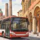 Un autobus urbano in una strada di Bologna, con i portici sullo sfondo, in un’illustrazione editoriale sullo sciopero dei trasporti del 30 ottobre.