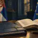 Un fascicolo diplomatico chiuso accanto a un volume costituzionale aperto, su un tavolo istituzionale.