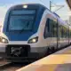 Treno regionale fermo su un binario in una stazione urbana bolognese