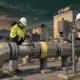 Illustrazione di due operatori presso una condotta e una valvola in un impianto gas.