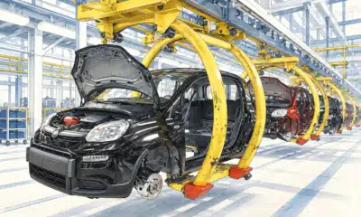 Illustrazione di un’automobile senza marchi in fase di assemblaggio su una linea industriale.