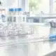 Illustrazione editoriale di un catetere per inseminazione intrauterina e di una piastra da laboratorio su un piano di lavoro chiaro.