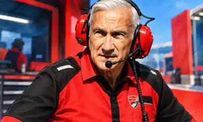 Ritratto illustrato di un dirigente Ducati in tuta rossa e nera, su uno sfondo essenziale ispirato a un box di MotoGP.