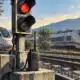 Illustrazione di un segnale ferroviario e di un dispositivo di comunicazione in primo piano, con due treni ad alta velocità sullo sfondo.