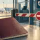 Un passaporto senza scritte riconoscibili davanti a un varco aeroportuale con la barriera abbassata.