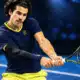 Una racchetta e una palla da tennis su un campo indoor blu, in un’illustrazione dedicata alla vittoria di Alcaraz su Khachanov a Vienna.